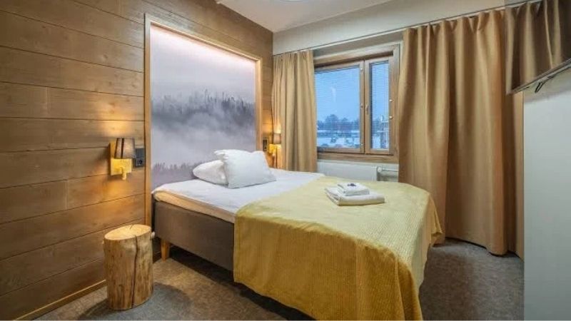 Standardrum p� Hotel Kultahippu i Ivalo med modern inredning, bekv�m s�ng, ljusa gardiner och f�nster med utsikt �ver Lapplands vinterlandskap.